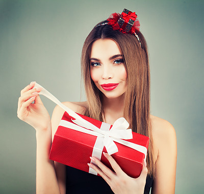 打开红色礼品盒。微笑女孩的完美妆容和发型图片下载