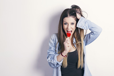 拿着心形棒棒糖的年轻女子。图片下载