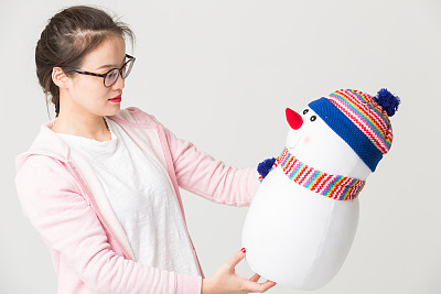 一个美丽的年轻女人抱着一个玩具雪人的肖像图片下载