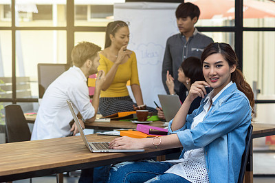 商业女性的肖像工作与电脑上的照片模糊的亚洲和多民族商务人士与休闲西装在现代办公室，人的商业集团的概念图片下载