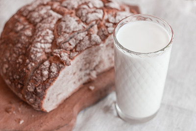 一杯牛奶和一个漂亮的纹理面包放在木砧板上。图片下载