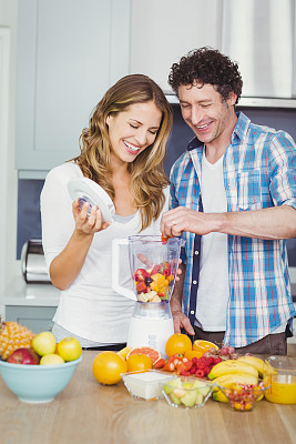 微笑的夫妇准备果汁图片下载