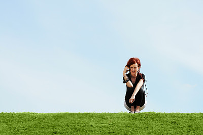 年轻女孩拿着手机坐在草地上图片下载