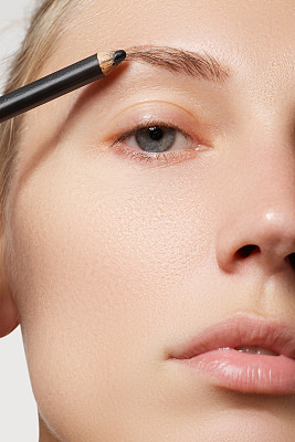 用化妆刷画眉毛的漂亮女人。化妆师给模特化妆图片下载