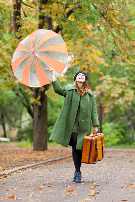 美丽的年轻女人的照片与伞和手提箱在美妙的秋天公园的背景图片下载