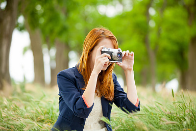 美丽的年轻女子的肖像拿着复古相机在美妙的公园背景图片下载