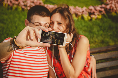 快乐的年轻夫妇在公园和自拍享受阳光灿烂的一天图片下载