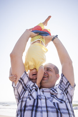 年轻英俊的父亲和儿子在海滩上玩图片下载