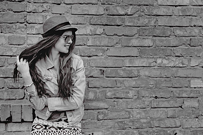 幸福美丽的女人站在旧砖墙附近。图片下载