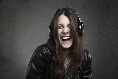 笑着的年轻女子戴着耳机听音乐图片下载