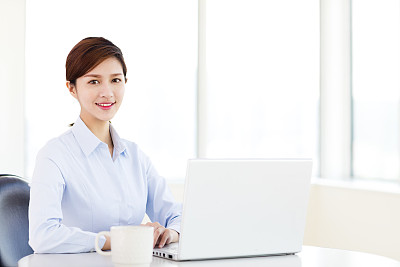 在办公室使用笔记本电脑的年轻女商人素材图片
