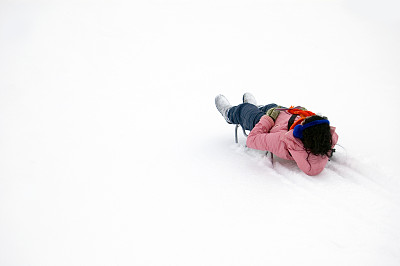 女孩坐着雪橇从山上滑下来图片下载