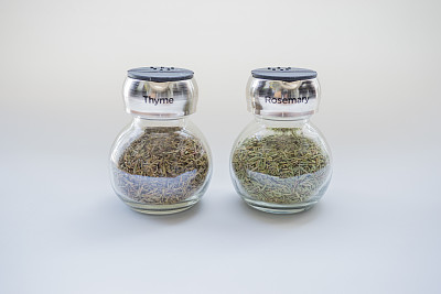 迷迭香和百里香在一个玻璃罐在白色的背景。图片下载