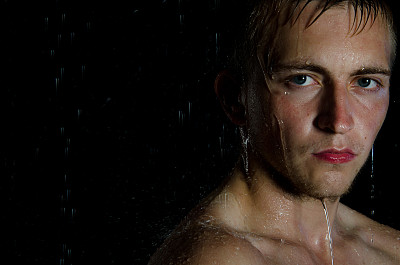 肖像。年轻人在淋浴间洗澡。的男人。身体和脸湿润。图片下载