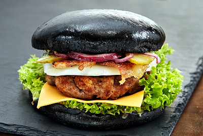 黑色的汉堡放在黑色背景的石头桌上。快餐餐。美味的汉堡。美味的汉堡包。图片下载