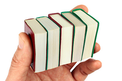 手里拿着小的迷你书，孤立在白茫茫之中图片下载