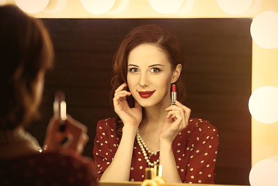 美丽的年轻女子拿着她的口红靠近窗户与灯光的照片图片下载