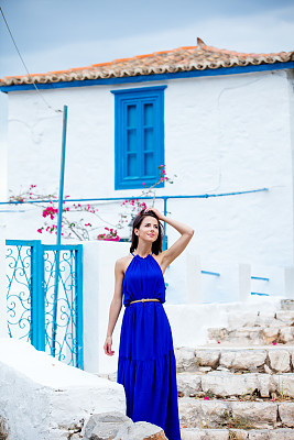 一张美丽的年轻女子站在希腊房子附近的楼梯上的照片图片下载