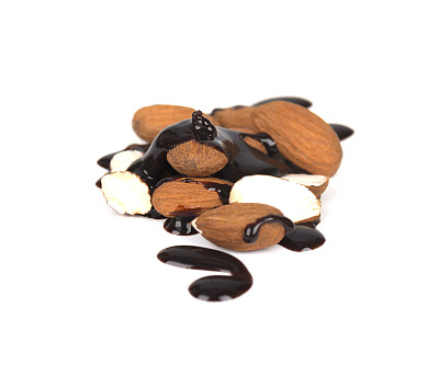 一堆去皮杏仁，滴有巧克力糖浆，在白色背景上隔离图片下载