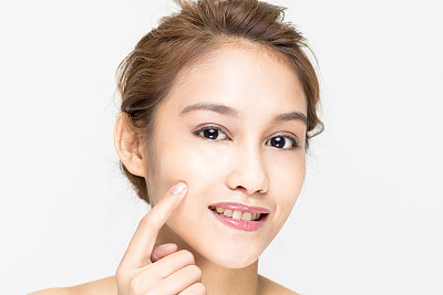 美丽的女孩一半拉丁和一半亚洲谁检查她的皮肤，皮肤护理，痤疮治疗素材图片