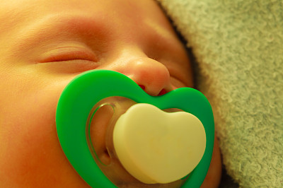 小新生儿叼着奶头睡觉的特写图片下载