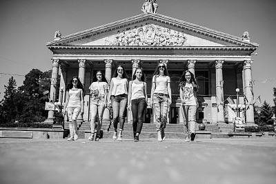 六个美丽的女孩从街上走出来，背景是一座宏伟的建筑。黑白照片。图片下载