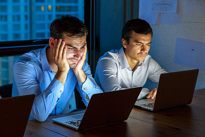 商务人士在办公室里用笔记本电脑工作到深夜图片下载