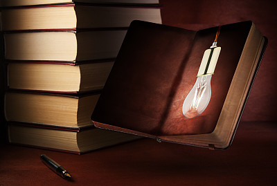 钢笔和打开的记事本放在一张木桌上。一个想法的概念，一个笔记本上的灯泡。图片下载