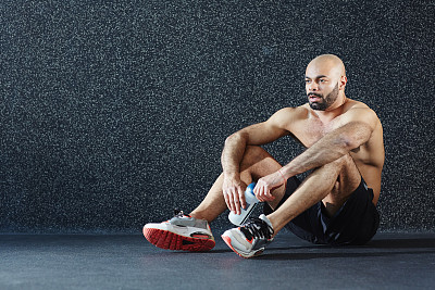 靠墙坐在地板上的肌肉男图片下载