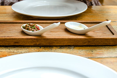 木板上白色勺子里的开胃菜图片下载