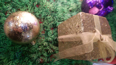 散焦的圣诞背景与一个金色和紫色的装饰品和礼物盒在绿色的背景图片下载