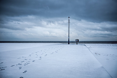 启蒙之路。白雪覆盖的沙滩上有脚印通向古色古香的灯柱。图片下载