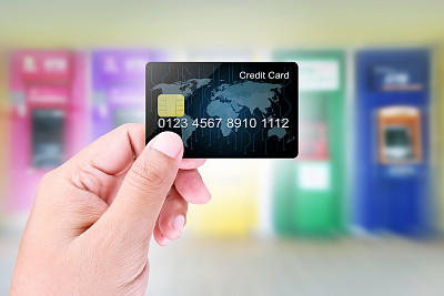 在模糊抽象的atm机背景上手持信用卡图片下载