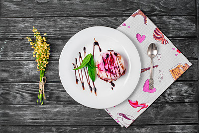 旧木桌上黄色的针织餐巾上放着一个盘子和勺子，上面放着水果果冻和杏子。有选择性的重点图片下载