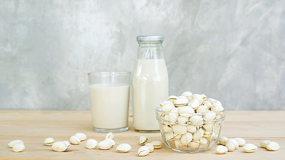 木桌上放着开心果牛奶。图片下载