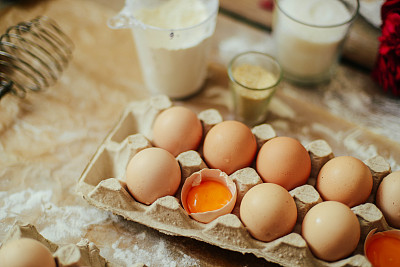 手在木桌上从生面团上切饼干。健康的烘焙材料-面粉，黄油，鸡蛋，饼干放在木桌上。素材图片