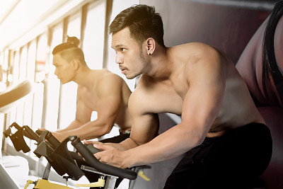 年轻人和朋友在健身房做动感单车运动图片下载