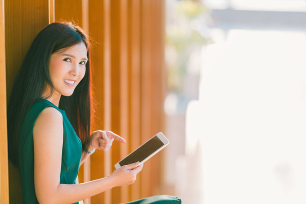 亚洲女商人或大学生在日落时分，在现代办公室或图书馆使用并指着平板电脑。商业交流，小工具技术，或教育概念与复制空间图片下载