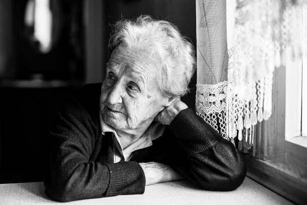 老妇人坐在厨房靠窗的地方，一张黑白照片。图片下载