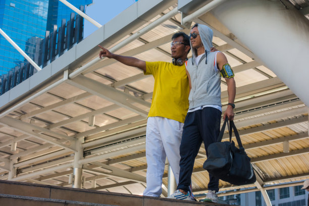 两个亚洲运动员看着并指着城市。图片下载