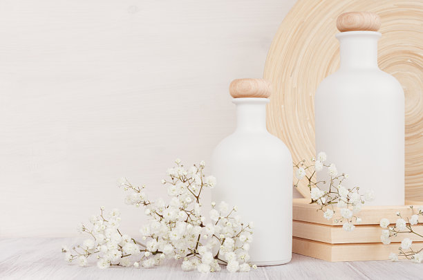 空白白色化妆品瓶与小花在白色木板，复制空间。内部。柔和优雅的家居装饰。图片下载