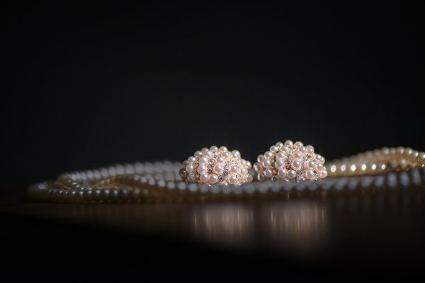 珍珠首饰，华丽的大耳环和双支架项链，优雅地展示在黑暗的背景下，表面柔和的反射图片下载