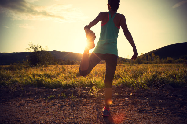 在日落森林跑步前，女跑步者伸展双腿图片下载