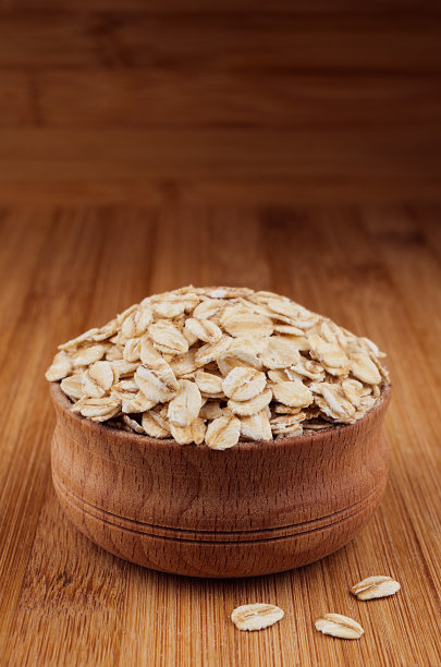 木碗里的燕麦片放在棕色的竹板上，特写。乡村风格，健康的饮食背景。图片下载