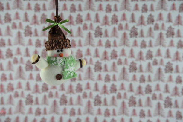 圣诞节照片可爱的雪人圣诞树装饰挂着红色和白色的圣诞包装纸为背景图片下载