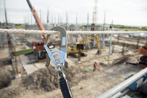 在高空设备工作。工人用防坠落装置，有选择焦点的安全体吊钩。工人作为背景。图片下载