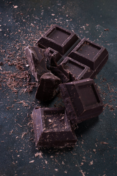 深色背景上的碎巧克力块和可可粉图片下载