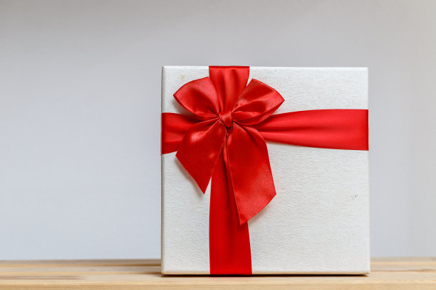 白色礼盒与红色丝带木制桌子背景图片下载