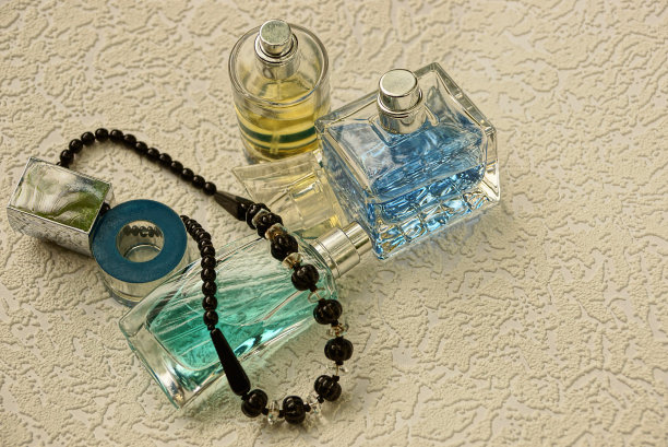 灰色背景上有彩色香水和黑色珠子的玻璃瓶图片下载