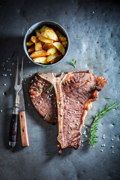 金属桌子上的自制骨牛排和薯条图片下载